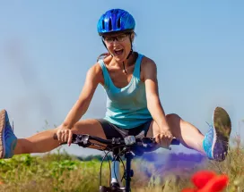 woman cycling through a meadow with he legs swinging out
