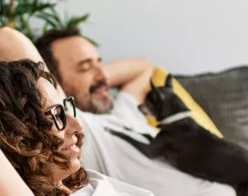 Man and woman relaxing on sofa with a dog