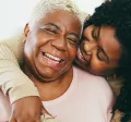 Old and young black women hugging and smiling
