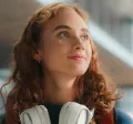 young woman looking happy with headphones around her neck