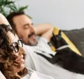 Man and woman relaxing on sofa with a dog