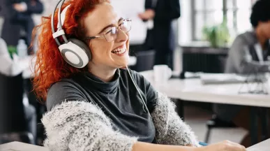 woman sat at desk with headphones