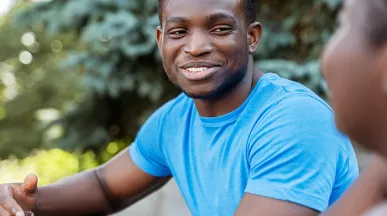black man in blue shirt smiling during a conversation with a black woman.