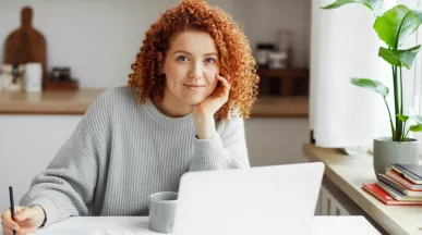 White woman with red curly hair on her laptop