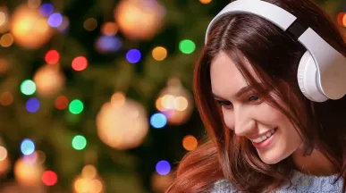 woman with headphones on with a Christmas tree in the background