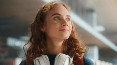 young woman looking happy with headphones around her neck