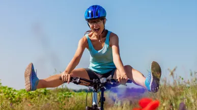 woman cycling through a meadow with he legs swinging out