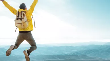 man on top of a mountain jumping in the air