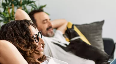 Man and woman relaxing on sofa with a dog