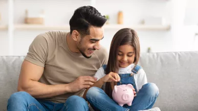 man with daughter saving some money in a piggy bank