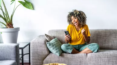 Woman on sofa looking at her phone and happy
