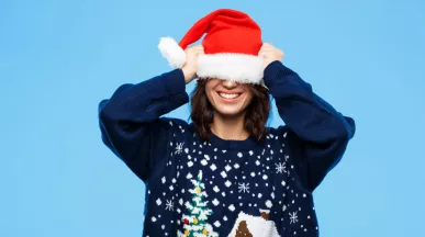 woman wearing an Xmas jumper pulling hat over head